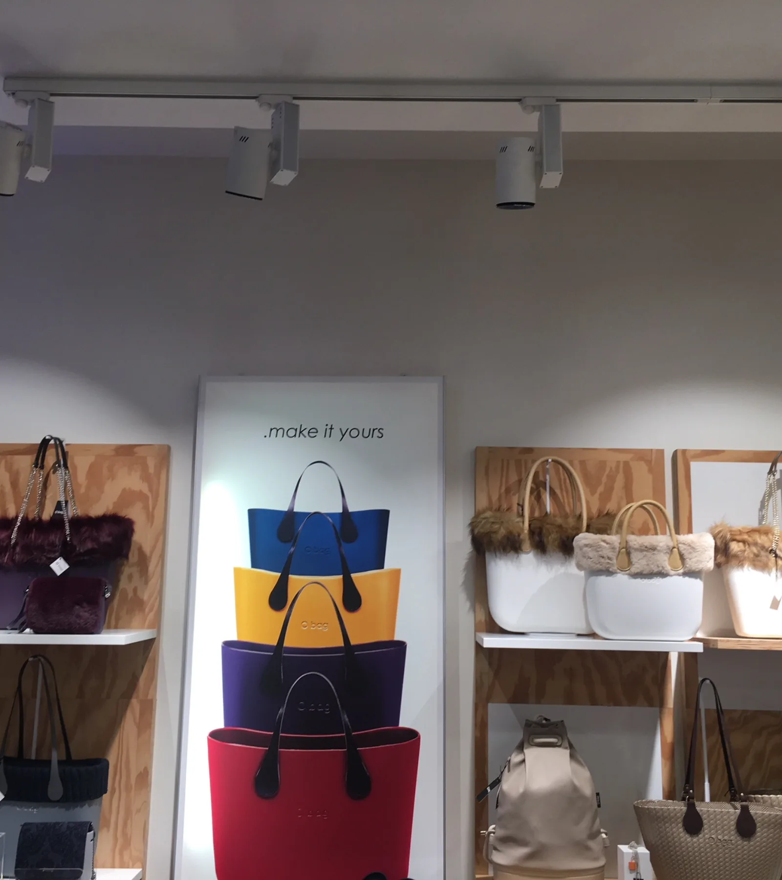 Borse_esposte_negozio_obag Esposizione di borse colorate su scaffali in legno chiaro in un negozio di moda. Homeled per o'bag