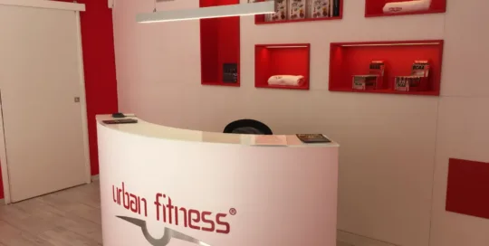 Reception moderna di una palestra Urban Fitness con design rosso e bianco.