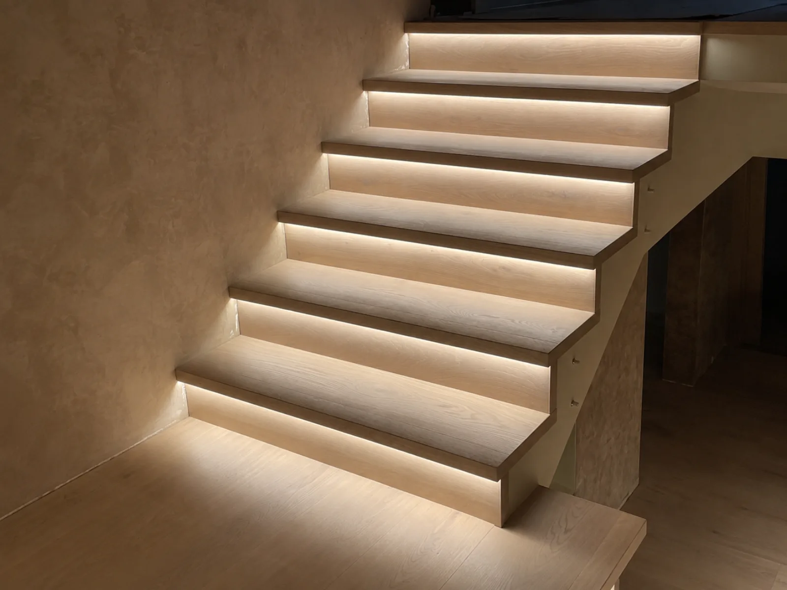 Scala moderna in legno con illuminazione a LED integrata lungo i bordi, in un ambiente interno.